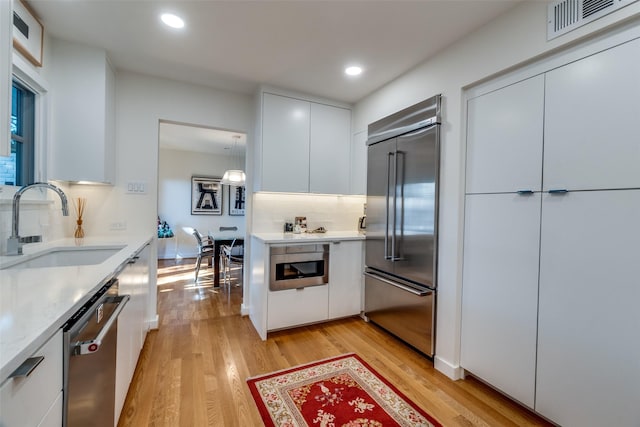 kitchen featuring sink, white cabinetry, stainless steel appliances, and light hardwood / wood-style flooring