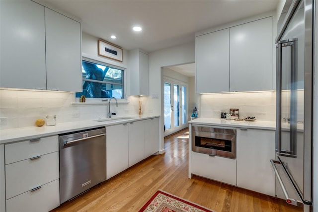 kitchen featuring white cabinetry, sink, light wood-type flooring, and appliances with stainless steel finishes