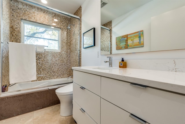 full bathroom featuring tile patterned floors, vanity, tiled shower / bath combo, and toilet