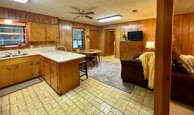 904 Uncas St, Logansport, LA 71049 - kitchen with sink, ceiling fan, wooden walls, a kitchen bar, and kitchen peninsula