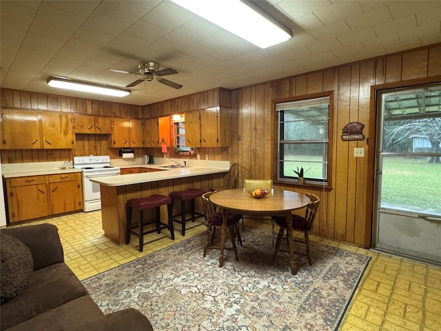904 Uncas St, Logansport, LA 71049 - kitchen with a kitchen breakfast bar, white electric range oven, kitchen peninsula, and wood walls
