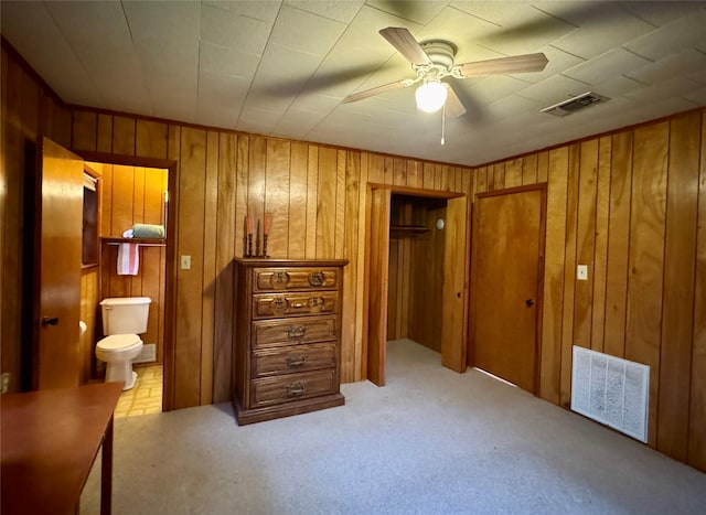 904 Uncas St, Logansport, LA 71049 - bedroom with ceiling fan, light colored carpet, ensuite bathroom, and wood walls