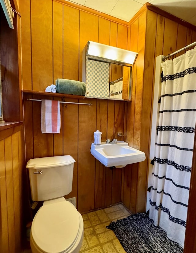 904 Uncas St, Logansport, LA 71049 - bathroom with toilet, sink, a shower with shower curtain, and wood walls