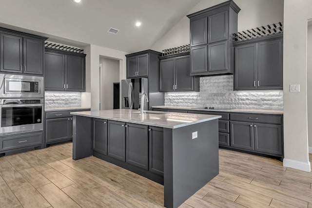 kitchen featuring decorative backsplash, sink, an island with sink, and appliances with stainless steel finishes