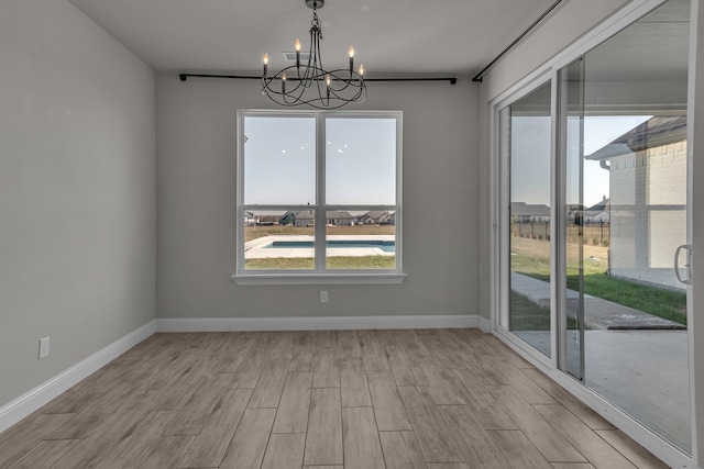 spare room featuring a chandelier and light wood-type flooring