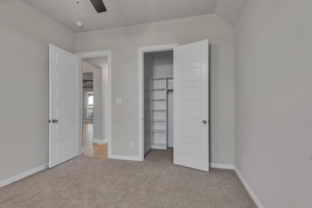 unfurnished bedroom with ceiling fan, a closet, lofted ceiling, and light carpet