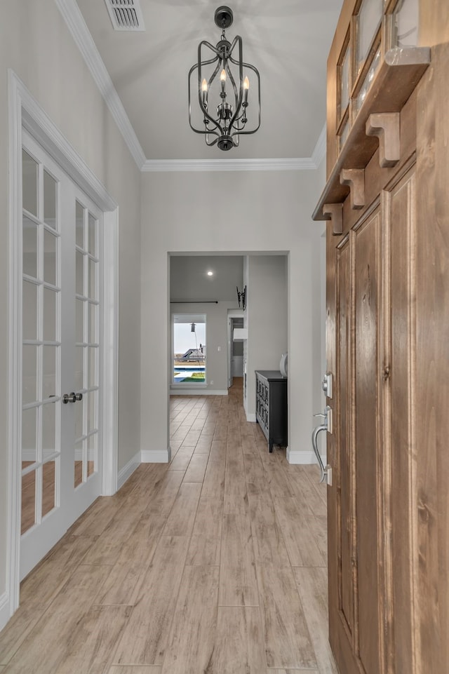 hall with a notable chandelier, crown molding, light hardwood / wood-style flooring, and french doors