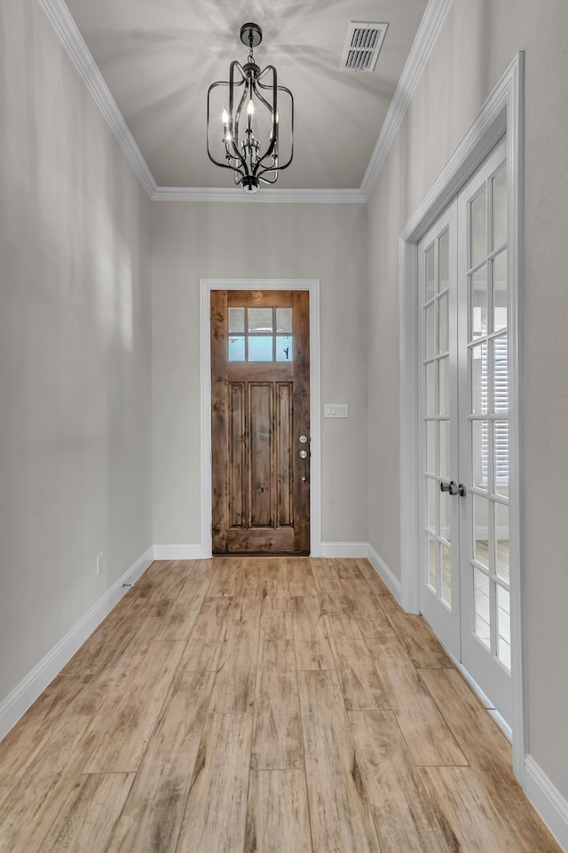 foyer featuring a chandelier, french doors, crown molding, and light hardwood / wood-style flooring