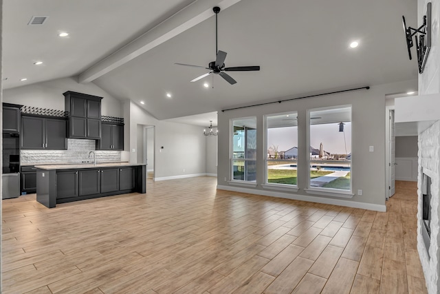 kitchen featuring a kitchen island with sink, beamed ceiling, ceiling fan with notable chandelier, and light wood-type flooring