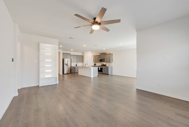 unfurnished living room featuring sink, ceiling fan, and light hardwood / wood-style flooring