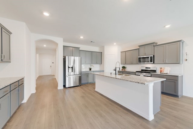 kitchen featuring stainless steel appliances, an island with sink, sink, and gray cabinetry