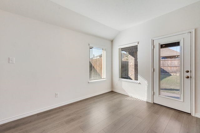 spare room with lofted ceiling and light hardwood / wood-style flooring