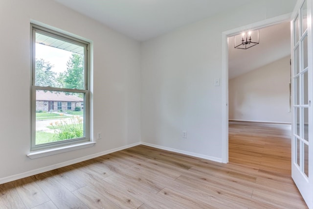 spare room with light hardwood / wood-style flooring, plenty of natural light, and an inviting chandelier