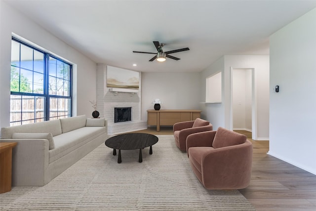 living room with a fireplace, light hardwood / wood-style flooring, and ceiling fan