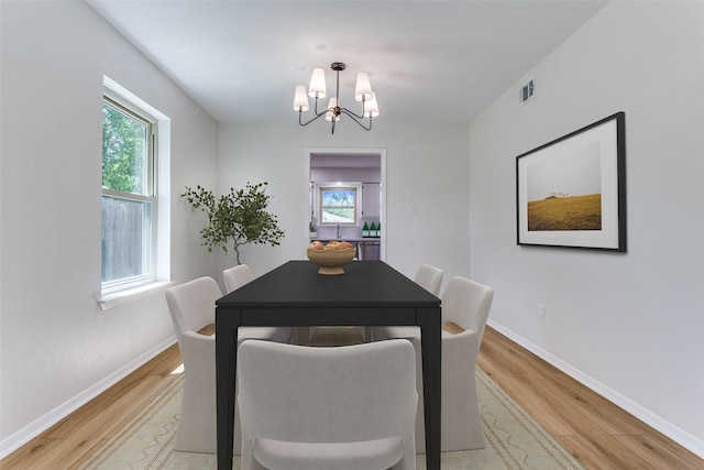 dining area with sink, a chandelier, and light wood-type flooring