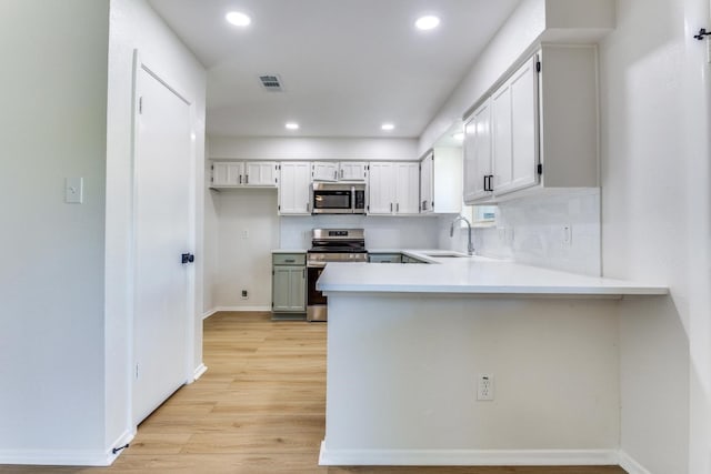 kitchen featuring white cabinetry, appliances with stainless steel finishes, sink, and light wood-type flooring