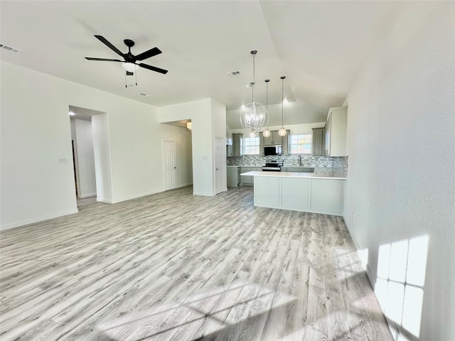 kitchen with stainless steel appliances, backsplash, pendant lighting, light hardwood / wood-style floors, and vaulted ceiling