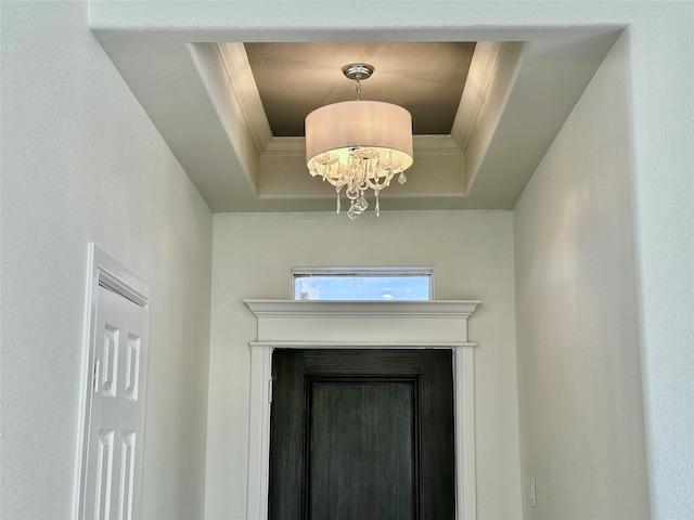 interior details with a raised ceiling, crown molding, and a notable chandelier