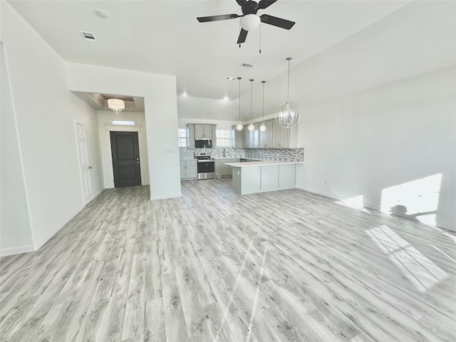 unfurnished living room with ceiling fan with notable chandelier and light hardwood / wood-style floors