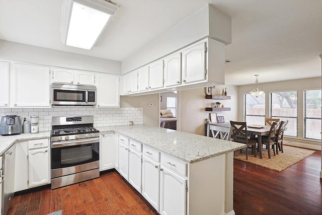 kitchen featuring stainless steel appliances, hanging light fixtures, white cabinets, and kitchen peninsula