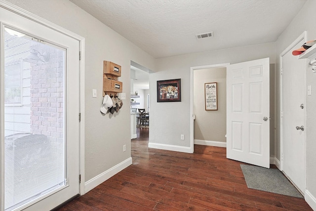 corridor with a healthy amount of sunlight, dark hardwood / wood-style floors, and a textured ceiling