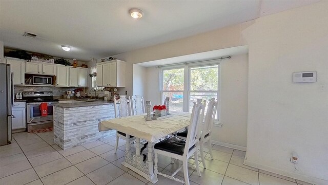 kitchen with sink, light tile patterned flooring, decorative backsplash, white cabinets, and appliances with stainless steel finishes