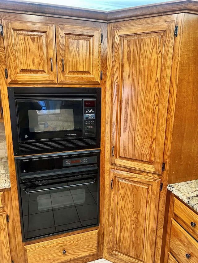 interior details featuring light stone counters and black appliances