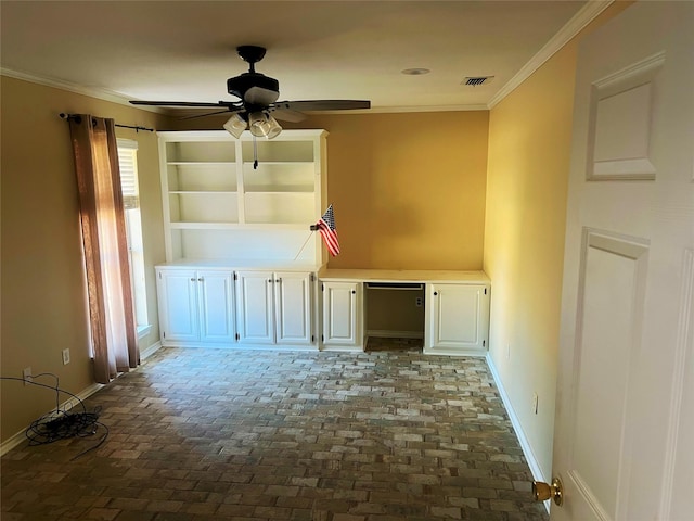 empty room featuring ornamental molding, built in desk, and ceiling fan