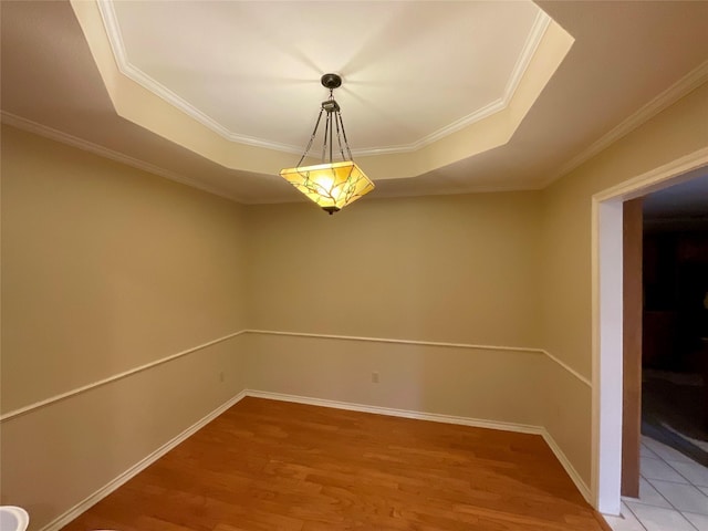 unfurnished room with crown molding, a tray ceiling, and wood-type flooring