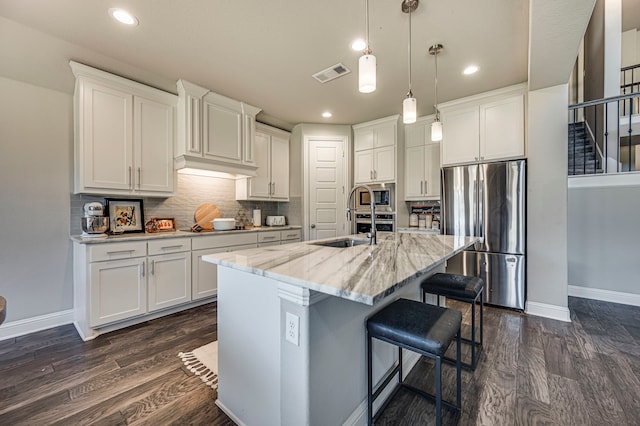 kitchen featuring white cabinets, stainless steel appliances, and an island with sink