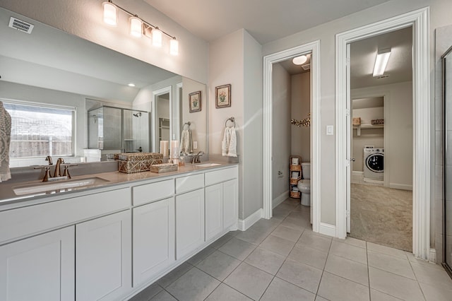 bathroom with washer / dryer, tile patterned floors, toilet, vanity, and a shower with shower door