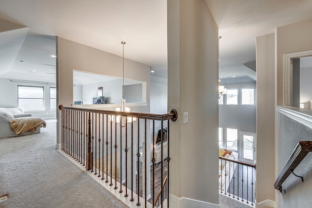 hallway with carpet and an inviting chandelier