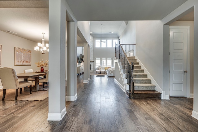 entryway with dark wood-type flooring and an inviting chandelier