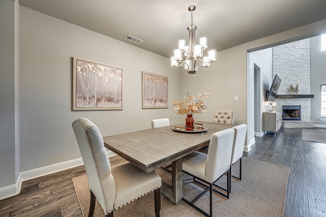 dining room featuring a fireplace, dark hardwood / wood-style floors, and a chandelier