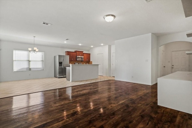 unfurnished living room with a notable chandelier and light wood-type flooring