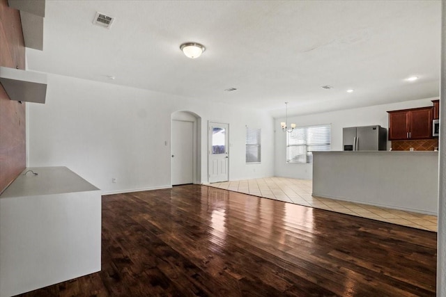 unfurnished living room with a chandelier and light hardwood / wood-style floors