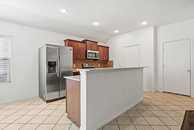 kitchen featuring backsplash, stainless steel appliances, a kitchen island, lofted ceiling, and light tile patterned flooring