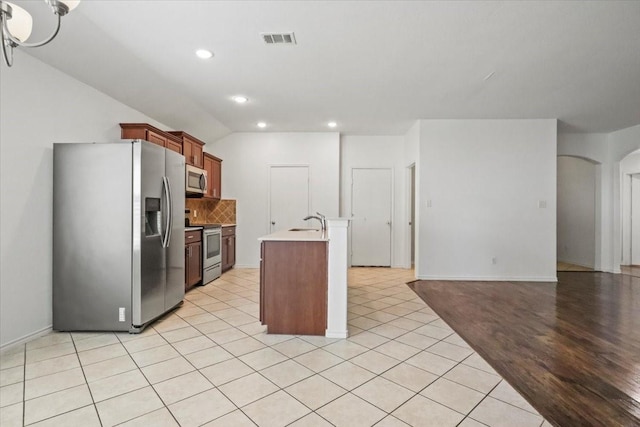 kitchen with sink, light wood-type flooring, stainless steel appliances, and an island with sink