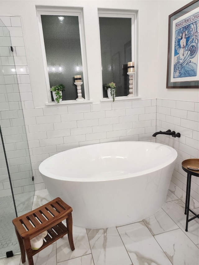 bathroom with tile walls and a tub