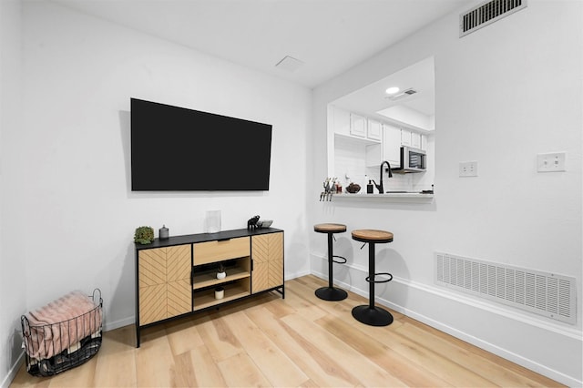 bar featuring white cabinets and light hardwood / wood-style floors