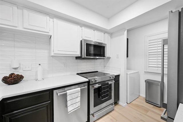 kitchen featuring stainless steel appliances, washer / dryer, decorative backsplash, white cabinets, and light wood-type flooring