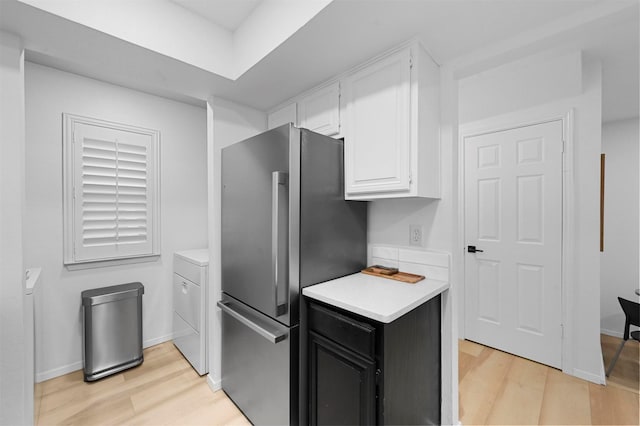 kitchen with stainless steel fridge, white cabinetry, light hardwood / wood-style flooring, and washer / clothes dryer