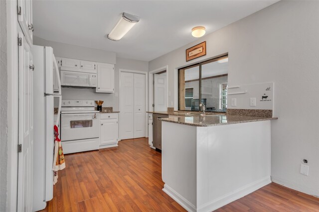 kitchen featuring kitchen peninsula, light hardwood / wood-style floors, stone countertops, white appliances, and white cabinets