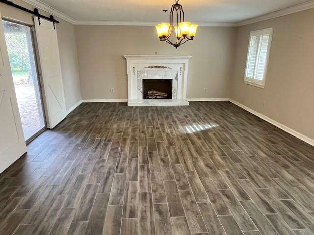 unfurnished living room with dark wood-type flooring, a barn door, and plenty of natural light