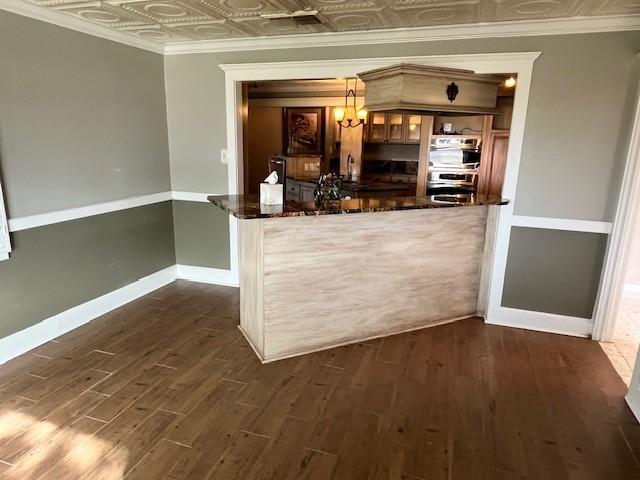 bar with crown molding, dark hardwood / wood-style floors, and decorative light fixtures