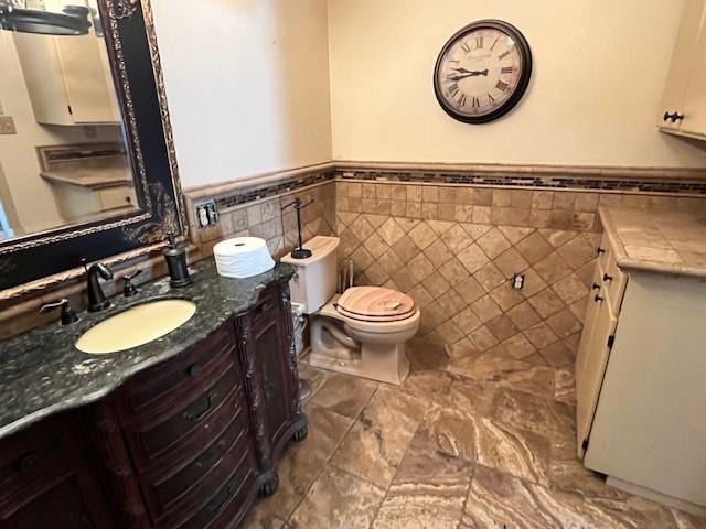 bathroom featuring vanity, tile walls, and toilet