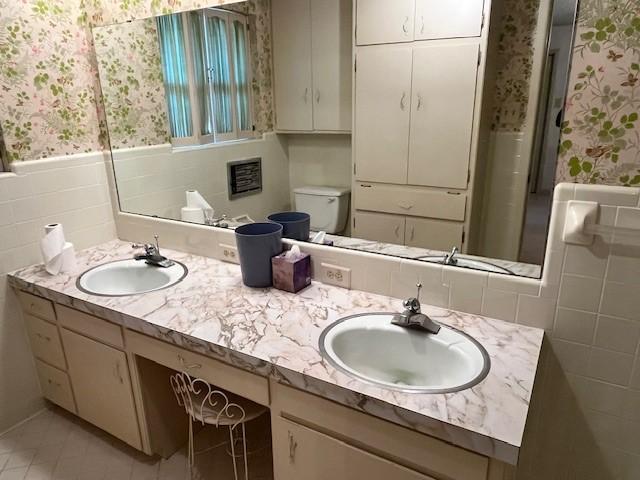 bathroom with vanity, toilet, and tile walls