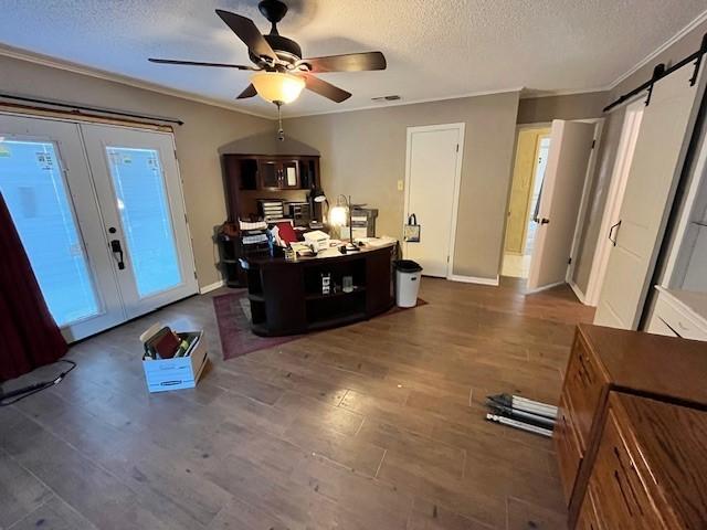 interior space featuring ceiling fan, a textured ceiling, french doors, dark hardwood / wood-style flooring, and a barn door