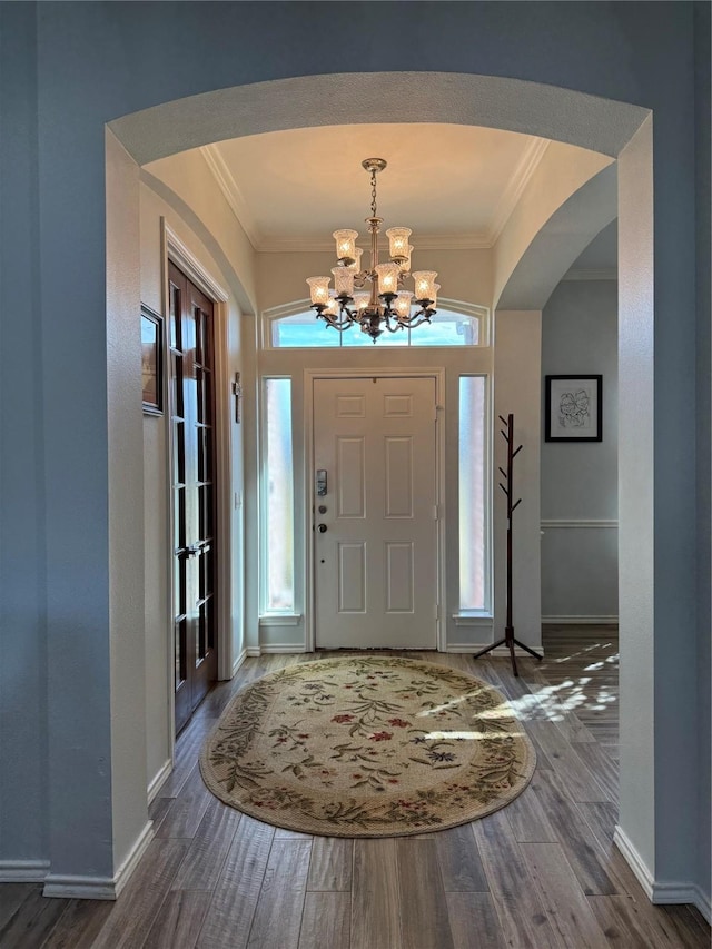 foyer entrance with crown molding, dark hardwood / wood-style flooring, and a notable chandelier