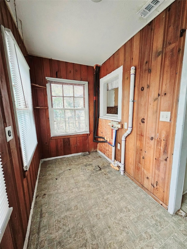 unfurnished room featuring wooden walls